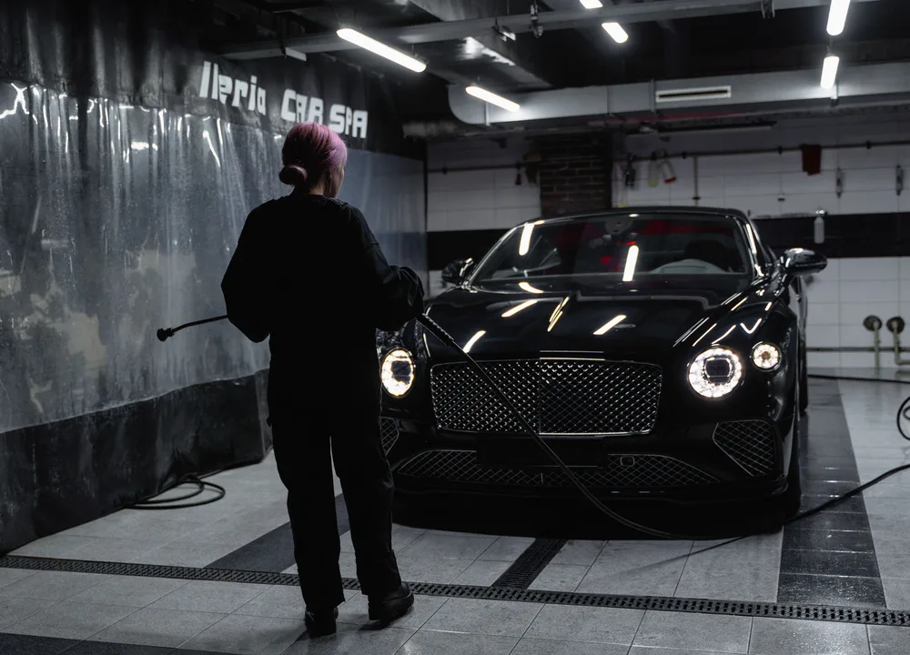Black luxury car being washed in a studio